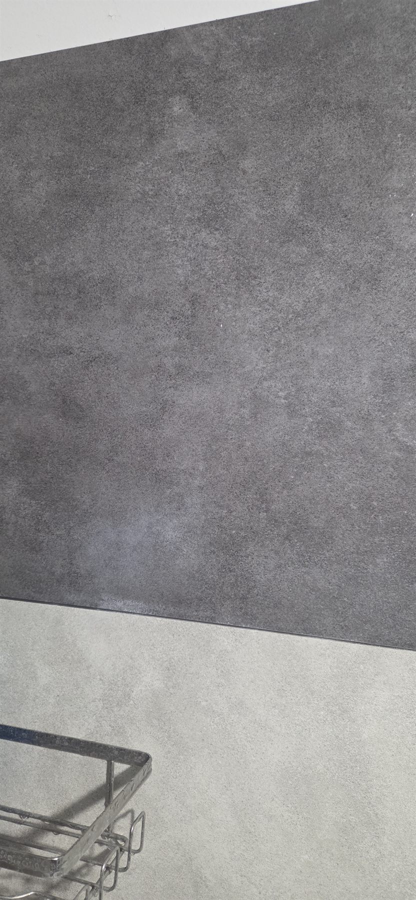 Gros plan sur une dalle Dumawall gris foncé avec un voile de calcaire en bas, au-dessus des dalles claires
