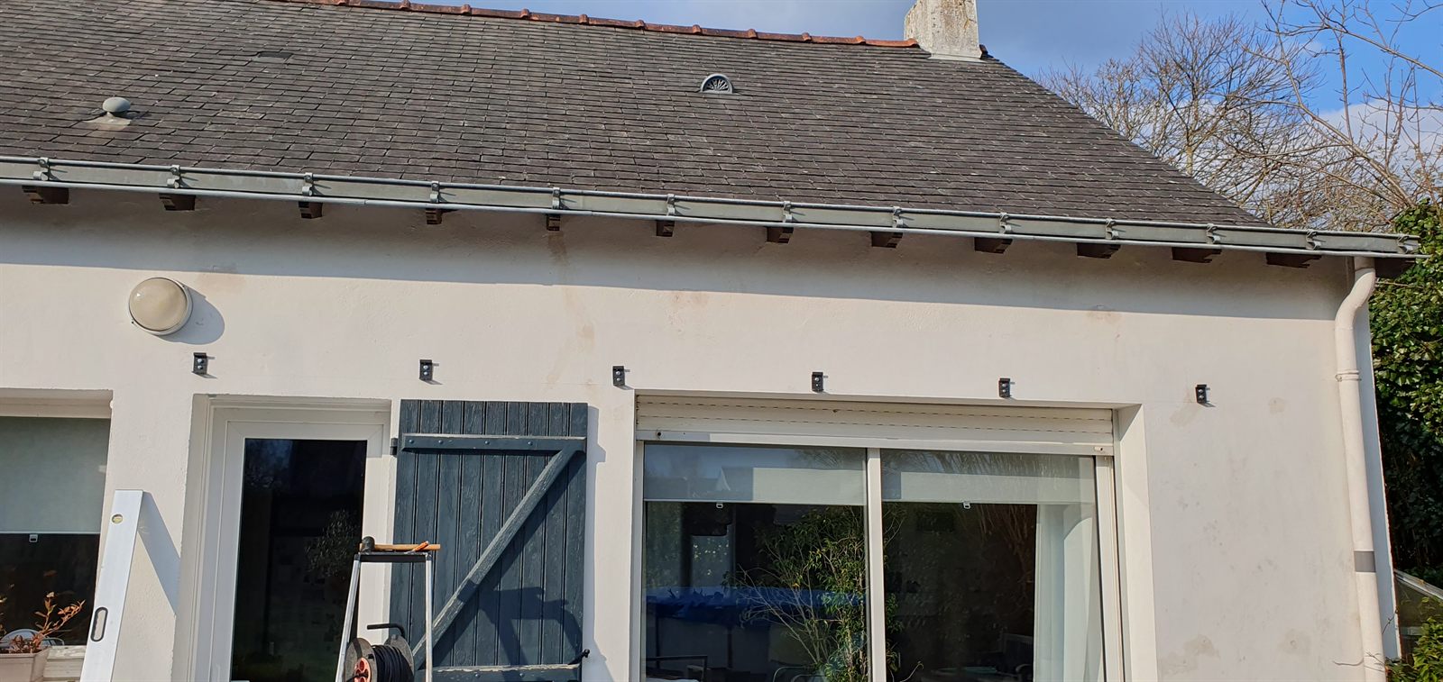 Six équerres de fixation alignées sur la façade, sous la gouttière