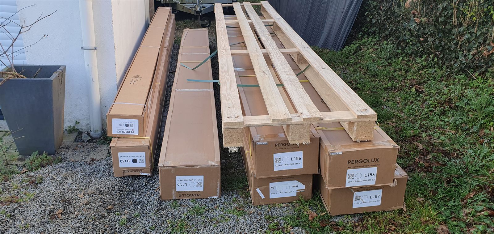 Cartons de la pergola Pergolux empilés dans le jardin après la livraison
